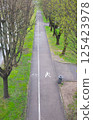 Bicycle and pedestrian asphalt paths in the city park, marked with special signs. Spring, greenery. Vertical photo 125423978