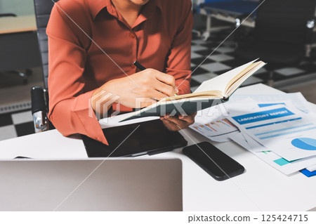 Working from home, Closeup business woman using laptop computer and analyzing financial report. 125424715