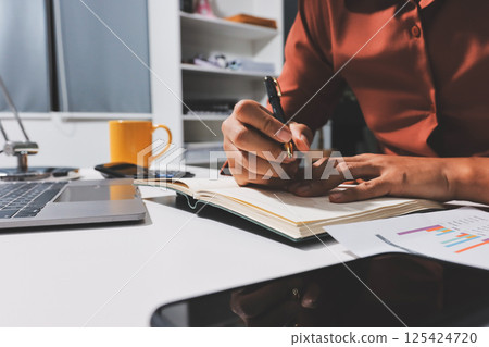 Working from home, Closeup business woman using laptop computer and analyzing financial report. Working from home, Closeup business woman using laptop computer and analyzing financial report. 125424720