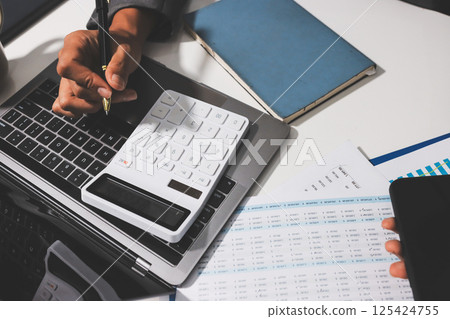 Working from home, Closeup business woman using laptop computer and analyzing financial report. Working from home, Closeup business woman using laptop computer and analyzing financial report. 125424755