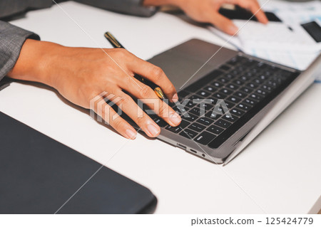 Working from home, Closeup business woman using laptop computer and analyzing financial report. 125424779