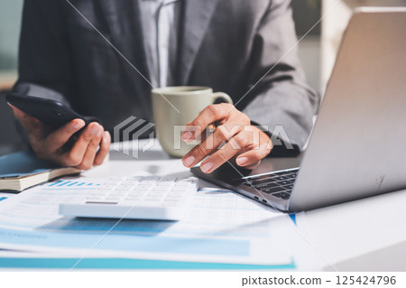 Working from home, Closeup business woman using laptop computer and analyzing financial report. 125424796