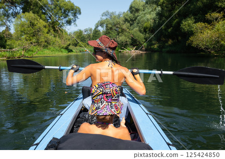 Family kayak trip. Mom and daughter rowing a boat on the river, a water hike, a summer adventure. Eco-friendly and extreme tourism, active and healthy lifestyle Family kayak trip. Mom and daughter rowing a boat on the river, a water hike, a summer adventure. Eco-friendly and extreme tourism, active and healthy lifestyle 125424850
