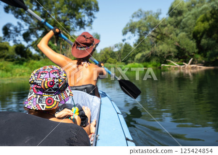 Family kayak trip. Mom and daughter rowing a boat on the river, a water hike, a summer adventure. Eco-friendly and extreme tourism, active and healthy lifestyle 125424854