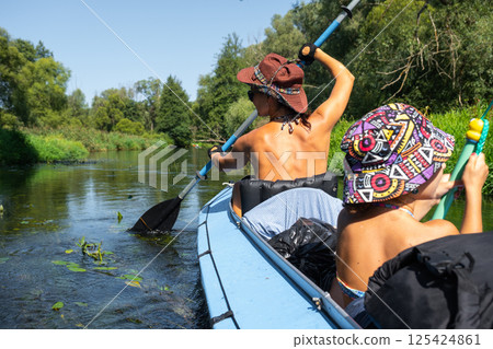 Family kayak trip. Mom and daughter rowing a boat on the river, a water hike, a summer adventure. Eco-friendly and extreme tourism, active and healthy lifestyle Family kayak trip. Mom and daughter rowing a boat on the river, a water hike, a summer adventure. Eco-friendly and extreme tourism, active and healthy lifestyle 125424861