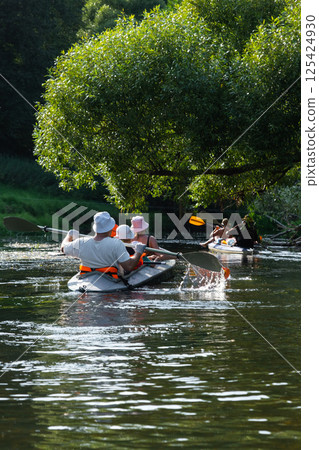 Family with children on rafting trip in Group kayak trip of different ages, adults, elderly. Rowing boat on the river, a water hike, summer adventure. 125424930