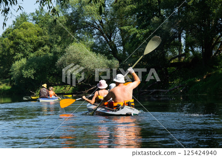 Family with children on rafting trip in Group kayak trip of different ages, adults, elderly. Rowing boat on the river, a water hike, summer adventure. 125424940