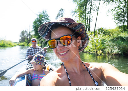 Man and woman couple, child 8 years old, selfies are happy in family kayak trip rowing boat on the river, water hike, a summer adventure. Eco-friendly and extreme tourism, active and healthy lifestyle Man and woman couple, child 8 years old, selfies are happy in family kayak trip rowing boat on the river, water hike, a summer adventure. Eco-friendly and extreme tourism, active and healthy lifestyle 125425034