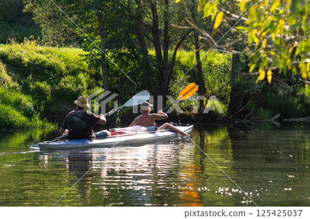 Kayak trip for an adult couple rowing boat on the river In the bright sunlight, a water hike, a summer adventure. 125425037