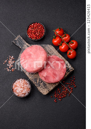 Two fresh slices of raw tuna fillet with spices and herbs Two fresh slices of raw tuna fillet with spices and herbs 125426415