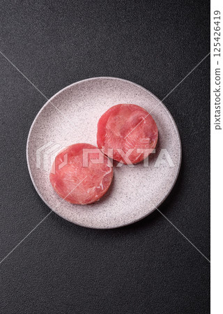 Two fresh slices of raw tuna fillet with spices and herbs Two fresh slices of raw tuna fillet with spices and herbs 125426419