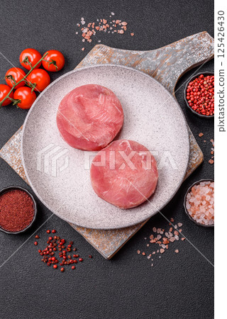 Two fresh slices of raw tuna fillet with spices and herbs Two fresh slices of raw tuna fillet with spices and herbs 125426430