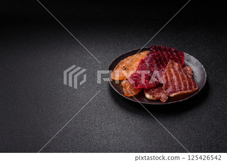 Jerky, dried meat in the form of slices with salt, spices and herbs Jerky, dried meat in the form of slices with salt, spices and herbs 125426542