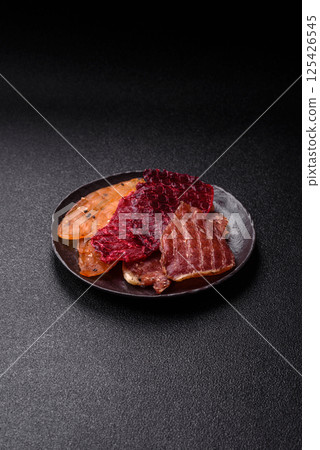 Jerky, dried meat in the form of slices with salt, spices and herbs 125426545