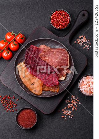 Jerky, dried meat in the form of slices with salt, spices and herbs Jerky, dried meat in the form of slices with salt, spices and herbs 125426555