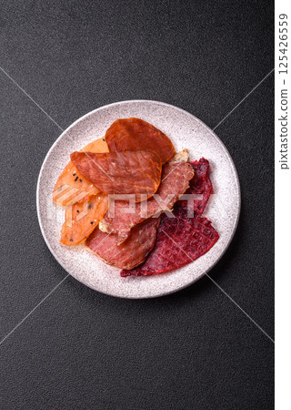 Jerky, dried meat in the form of slices with salt, spices and herbs 125426559