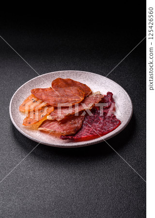 Jerky, dried meat in the form of slices with salt, spices and herbs Jerky, dried meat in the form of slices with salt, spices and herbs 125426560