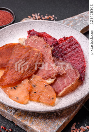 Jerky, dried meat in the form of slices with salt, spices and herbs Jerky, dried meat in the form of slices with salt, spices and herbs 125426568