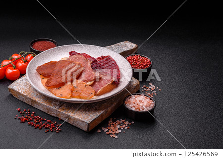 Jerky, dried meat in the form of slices with salt, spices and herbs Jerky, dried meat in the form of slices with salt, spices and herbs 125426569
