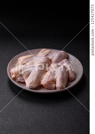 Raw chicken wings with salt, spices and herbs Raw chicken wings with salt, spices and herbs 125427073