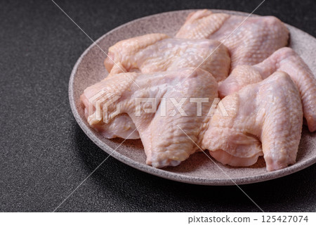 Raw chicken wings with salt, spices and herbs Raw chicken wings with salt, spices and herbs 125427074