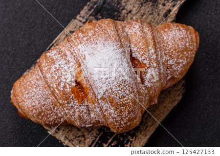 Sweet fresh crispy croissant with fruit filling 125427133