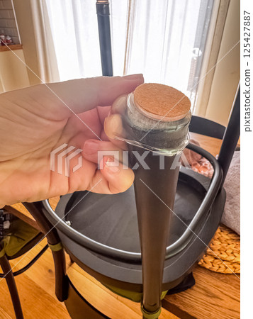 Attaching cork pad to chair leg for floor protection and noise reduction indoors. High quality photo 125427887