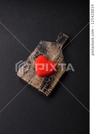 Red wax candle in the shape of a heart as decor for Valentine's Day Red wax candle in the shape of a heart as decor for Valentine's Day 125428814
