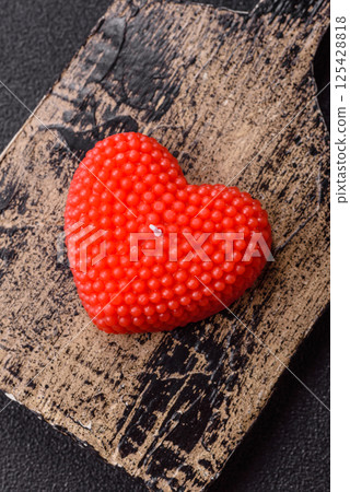 Red wax candle in the shape of a heart as decor for Valentine's Day 125428818