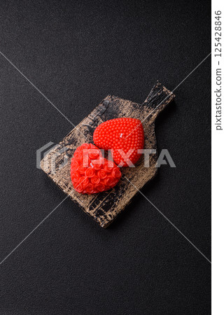 Red wax candle in the shape of a heart as decor for Valentine's Day 125428846