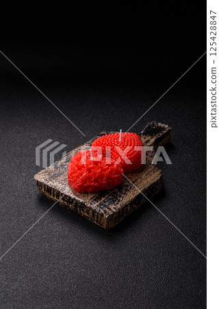 Red wax candle in the shape of a heart as decor for Valentine's Day Red wax candle in the shape of a heart as decor for Valentine's Day 125428847