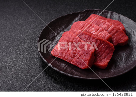 Raw beef tenderloin cut into slices with salt and spices 125428931