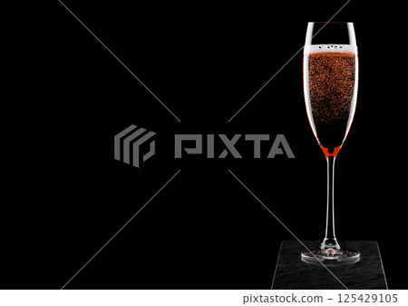Elegant glass of pink rose champagne with bubbles on black marble board on black background. Elegant glass of pink rose champagne with bubbles on black marble board on black background. 125429105