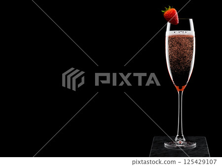 Elegant glass of pink rose champagne with strawberry on top on black marble board on black 125429107