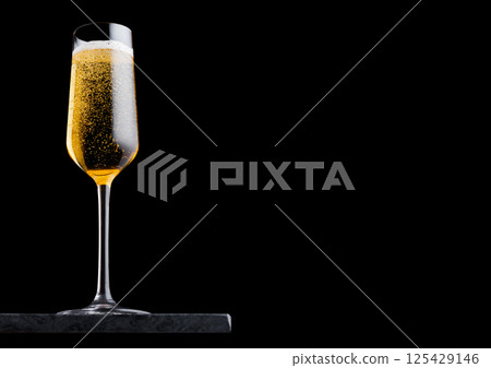 Elegant glass of yellow champagne with bubbles on blavk marble board on black background. Elegant glass of yellow champagne with bubbles on blavk marble board on black background. 125429146