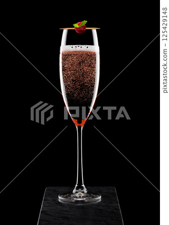 Elegant glass of pink rose champagne with raspberry on stick on black marble board on black Elegant glass of pink rose champagne with raspberry on stick on black marble board on black 125429148