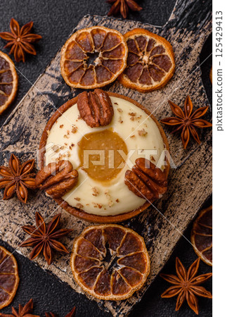 Sweet round tart with white citrus cream and pecans 125429413