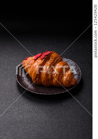 Sweet crispy croissant decorated with red hearts 125429426