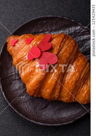 Sweet crispy croissant decorated with red hearts 125429435