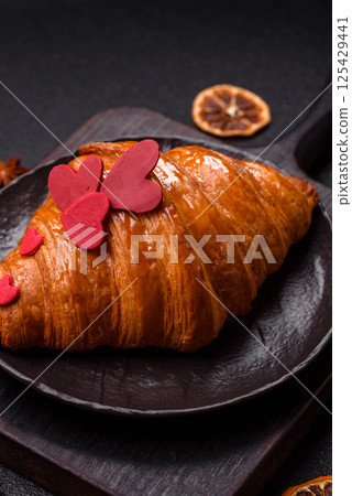Sweet crispy croissant decorated with red hearts 125429441
