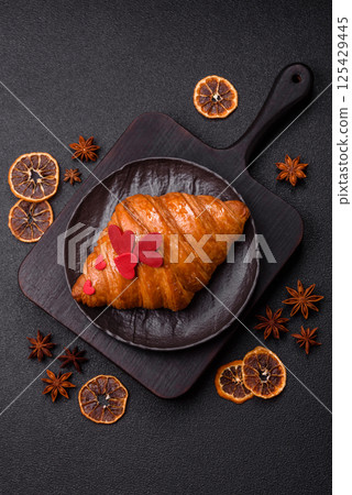 Sweet crispy croissant decorated with red hearts 125429445