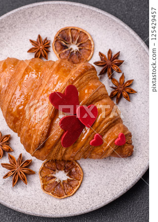 Sweet crispy croissant decorated with red hearts 125429457