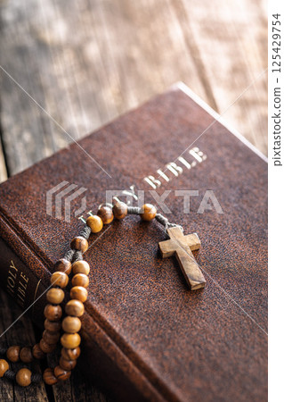 Wooden rosary beads and Holy Bible on wooden table. Wooden rosary beads and Holy Bible on wooden table. 125429754