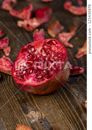 sliced red pomegranate on a table, sweet red pomegranate cut into pieces during cooking, close up 125430976