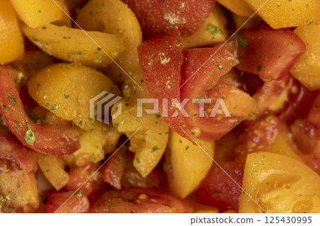 cut tomatoes of red and yellow color during salad preparation, preparation of salad from sliced tomatoes with spices and oil cut tomatoes of red and yellow color during salad preparation, preparation of salad from sliced tomatoes with spices and oil 125430995