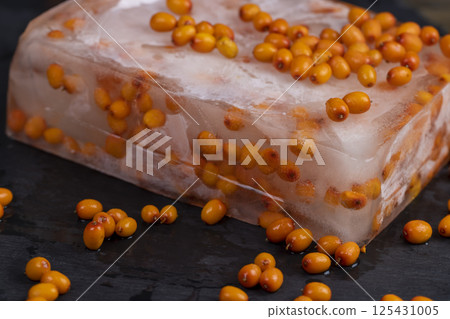 sea buckthorn berries closeup, sea buckthorn berries during deep freezing and scattered melted berries 125431005