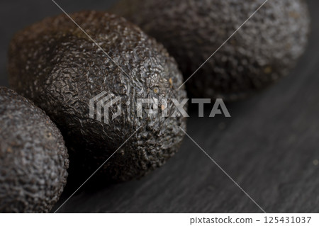 whole avocado fruits of small size on a black slate whole avocado fruits of small size on a black slate 125431037