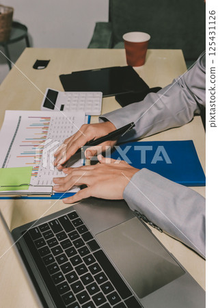 Working from home, Closeup business woman using laptop computer and analyzing financial report. Working from home, Closeup business woman using laptop computer and analyzing financial report. 125431126