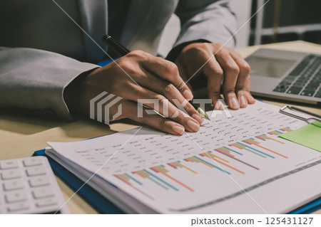 Working from home, Closeup business woman using laptop computer and analyzing financial report. Working from home, Closeup business woman using laptop computer and analyzing financial report. 125431127