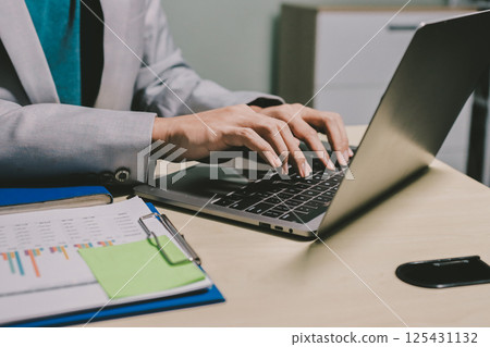 Working from home, Closeup business woman using laptop computer and analyzing financial report. 125431132